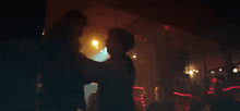 a man and a woman are looking at each other in a dark room .
