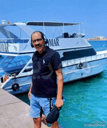a man wearing headphones is standing in front of a boat that says omar