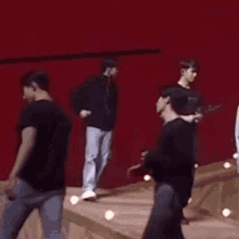 a group of men are standing on a stage in front of a red curtain .
