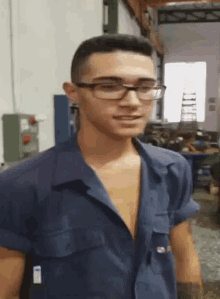 a man wearing glasses and a blue shirt with the letter a on the sleeve