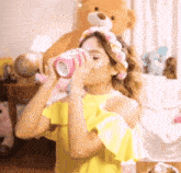 a woman in a yellow top is drinking from a pink cup .