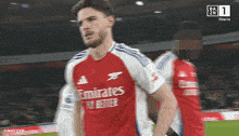 a soccer player wearing a red and white emirates jersey
