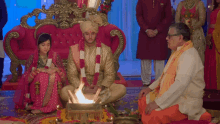 a bride and groom are sitting in front of a fire at their wedding