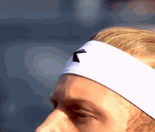 a close up of a man wearing a headband with a black arrow on it