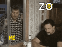 two men are sitting at a table with a bottle of alcohol and looking out of a window .