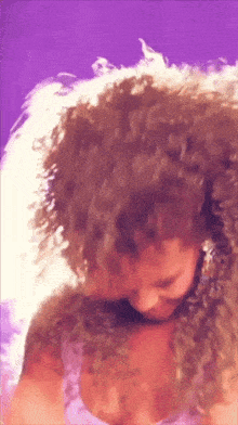 a woman with curly hair is wearing a pink top