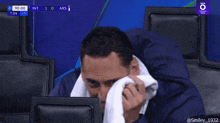a man with a towel around his neck is smiling while watching a game
