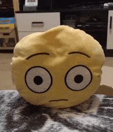 a yellow pillow with a face on it is sitting on a table