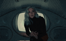 a woman in a black turtleneck is standing in a dark room