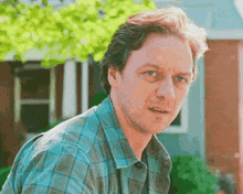 a man in a blue plaid shirt is looking at the camera .