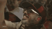 a man wearing sunglasses and a hat with the word coachella on the bottom left