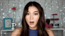 a woman with a surprised look on her face is wearing a blue top with the words pairin wonderland on the bottom