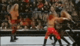 a group of wrestlers are fighting in a ring with a crowd watching .