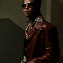 a man wearing sunglasses and a leather jacket smoking a cigarette