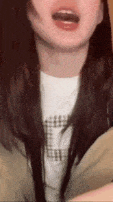 a close up of a woman 's face with her mouth open and a plaid shirt on .