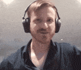 a man with a beard wears headphones and looks at the camera