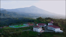 an aerial view of a school with mountains in the background and a soccer field in the foreground