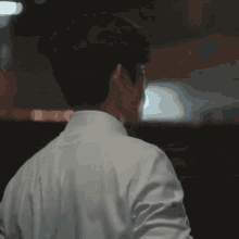 a man in a white shirt and glasses is standing in front of a building .