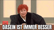 a judge with red hair and glasses is sitting in a courtroom with a sign that says dasein ist immer besser .