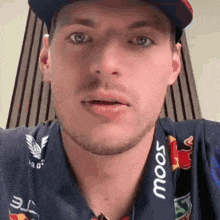a close up of a man wearing a hat and a shirt with the word moos on it