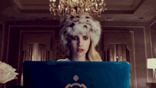 a woman wearing a fur hat is using a blue laptop