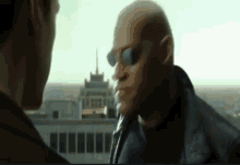 two men are standing next to each other with a building in the background