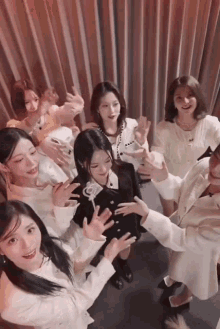 a group of women are standing in a circle with their hands outstretched .