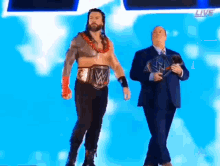 a man in a suit is standing next to a wrestler with a belt