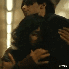 a man is holding a woman in his arms in a room in a netflix trailer .