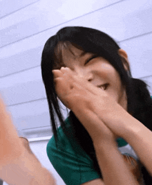 a woman is covering her face with her hands and smiling .