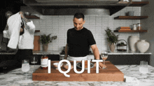 a man standing in a kitchen with a sign that says " i quit " on it