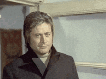 a man in a black coat looks at the camera