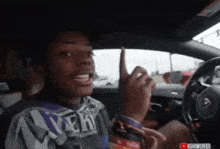 a young man is sitting in a car giving the middle finger