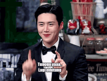 a man in a tuxedo and bow tie is giving the middle finger