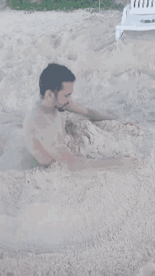 a shirtless man is buried in a pile of sand