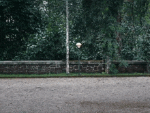 a brick wall with trees in the background and a lamp post in the foreground