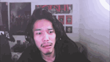 a man wearing headphones is making a funny face in front of a poster that says ' oishi '
