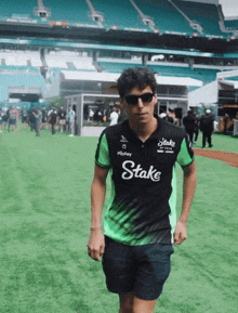 a man wearing a black and green shirt that says stake on it