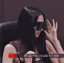 a woman wearing sunglasses and a ring has the word sara on her arm