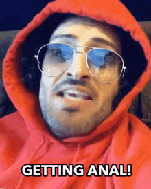 a man wearing a red hoodie and sunglasses says " getting anal "
