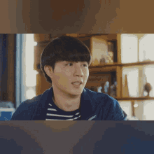 a young man in a striped shirt and a blue jacket