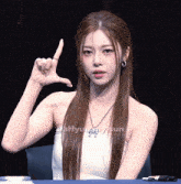 a woman sitting at a table with a sign on her finger that says ' i love you '