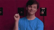 a young man in a blue shirt is standing in front of a red locker with the word falsa on it .