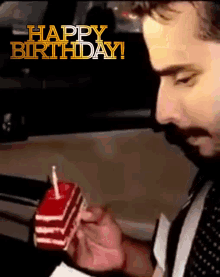 a man lighting a candle on a birthday cake with the words happy birthday behind him