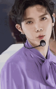 a close up of a person wearing a purple shirt with a microphone around their neck