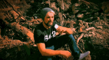 a man wearing a black shirt with the number 62 on it sits on a pile of rocks