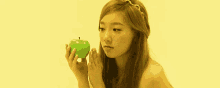 a woman is holding a green apple and looking at it