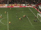 a soccer goalie jumps to catch a ball in front of a sign that says workwear russia.com