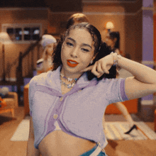 a woman wearing a purple crop top is making a funny face