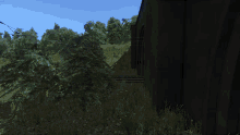 a blue train is parked in a grassy area next to a building